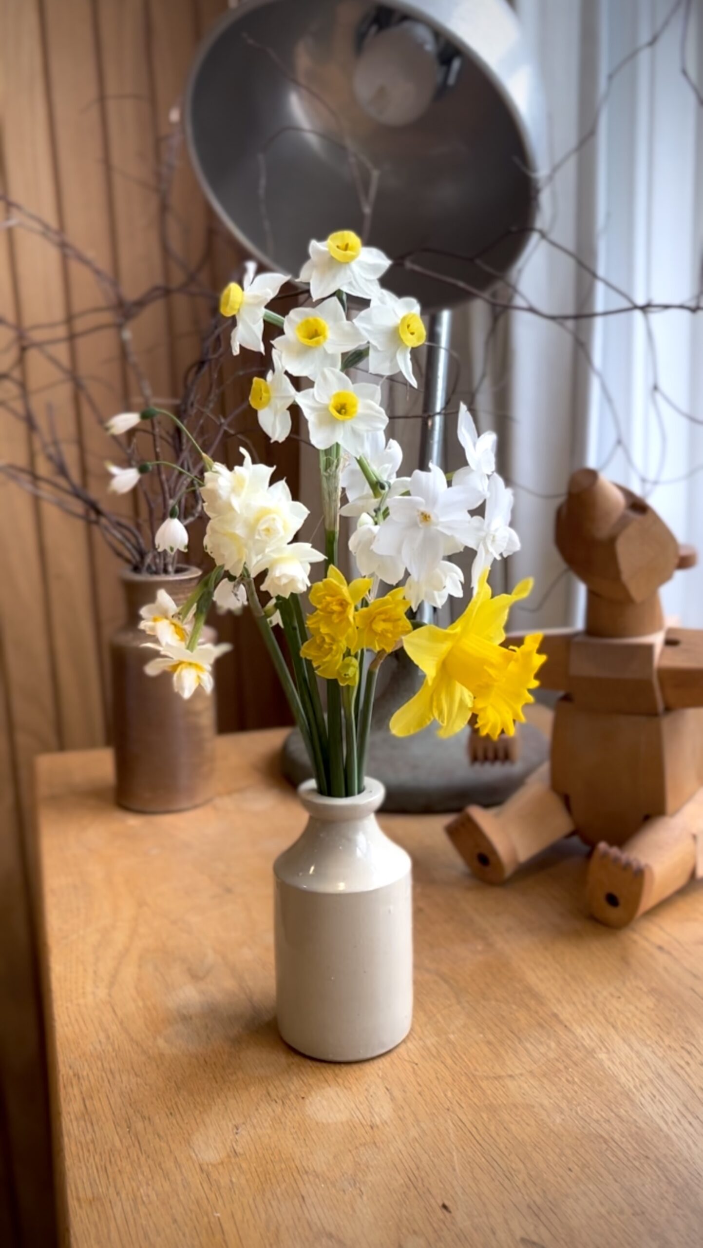 Fresh cut Daffodil and branch arrangement Spring daffodils and bare branches arranged in a ceramic vase as a rustic floral centerpiece