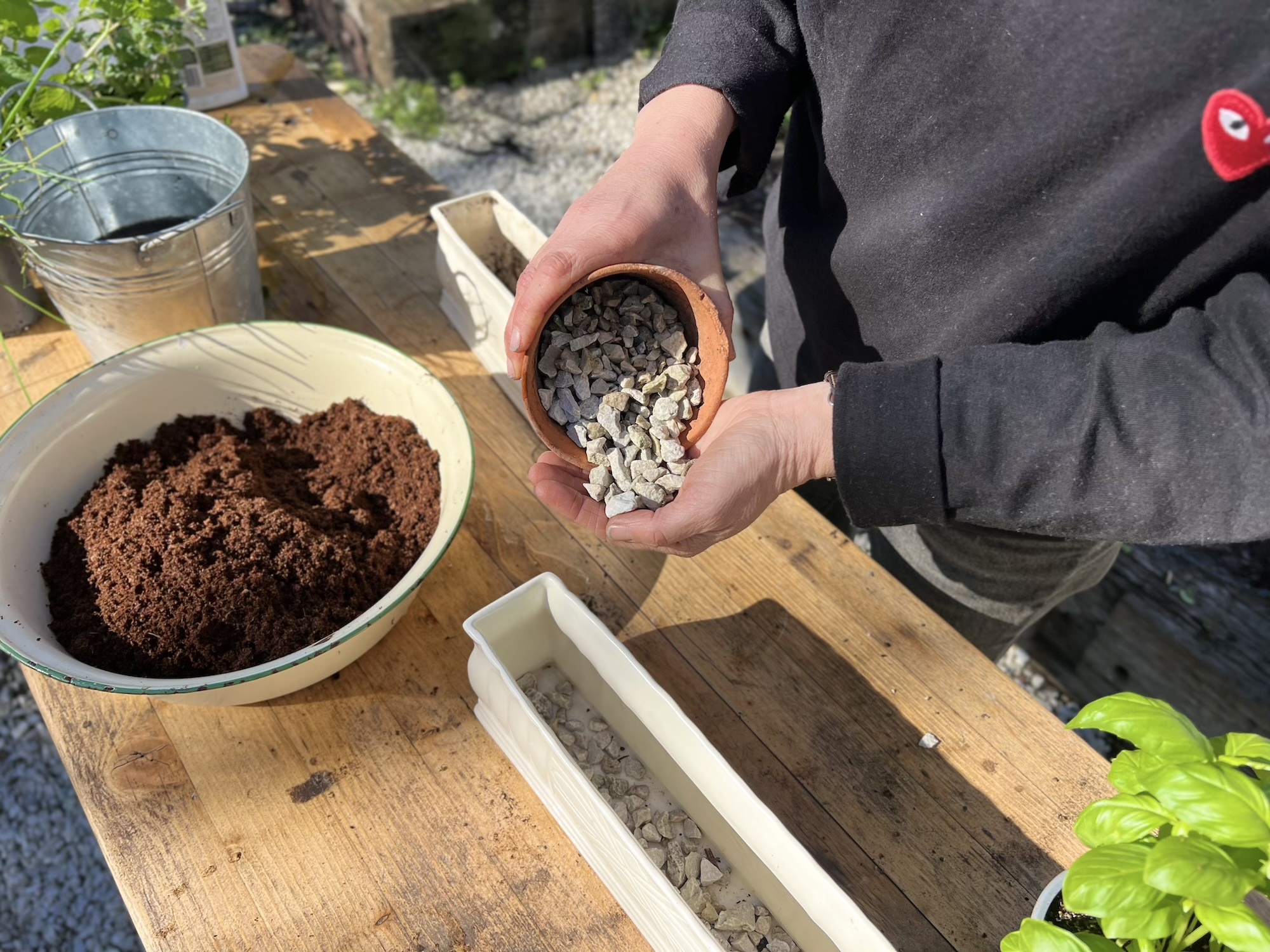 Preparing Gravel Drainage for Plante Gardener adding gravel stones to a planter as a base layer for herb planting.