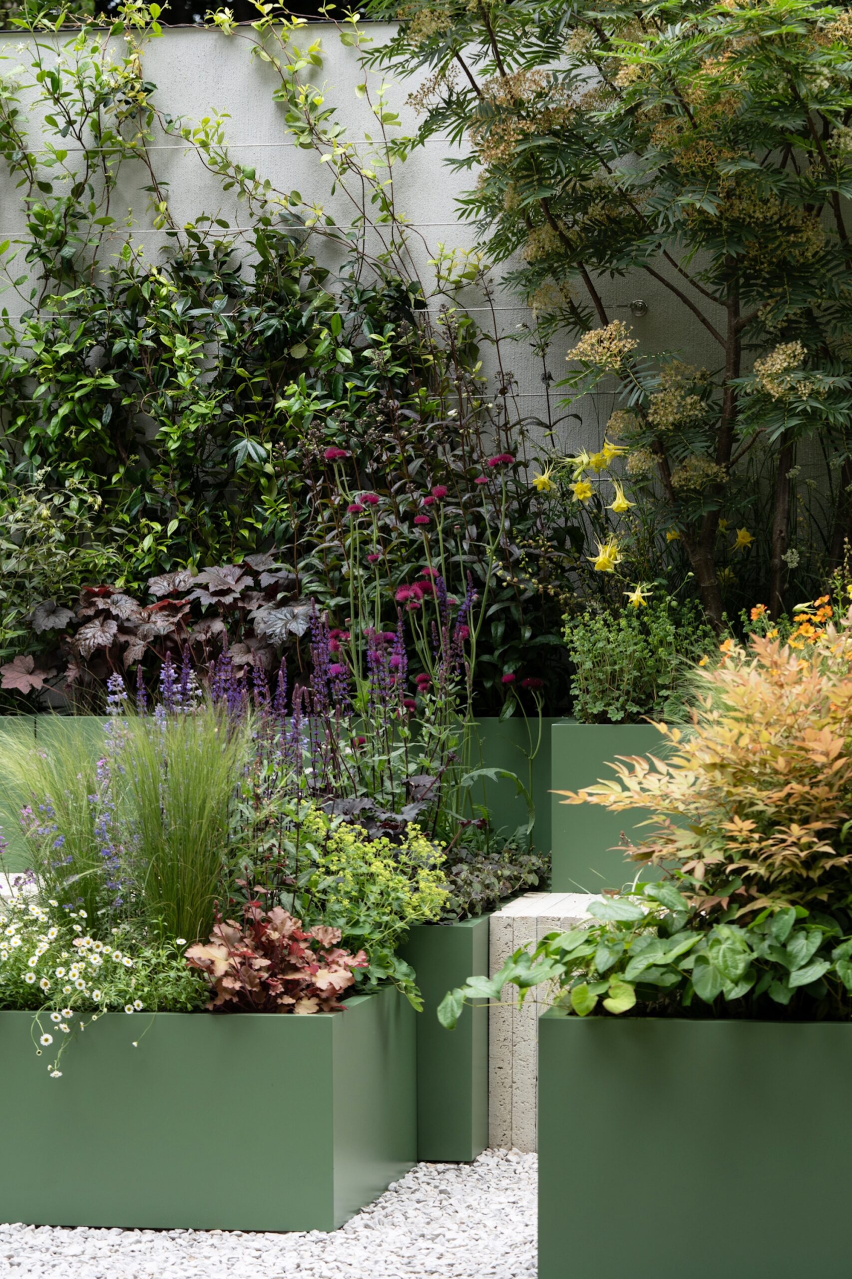 Group of raised metal planters with lush, diverse planting