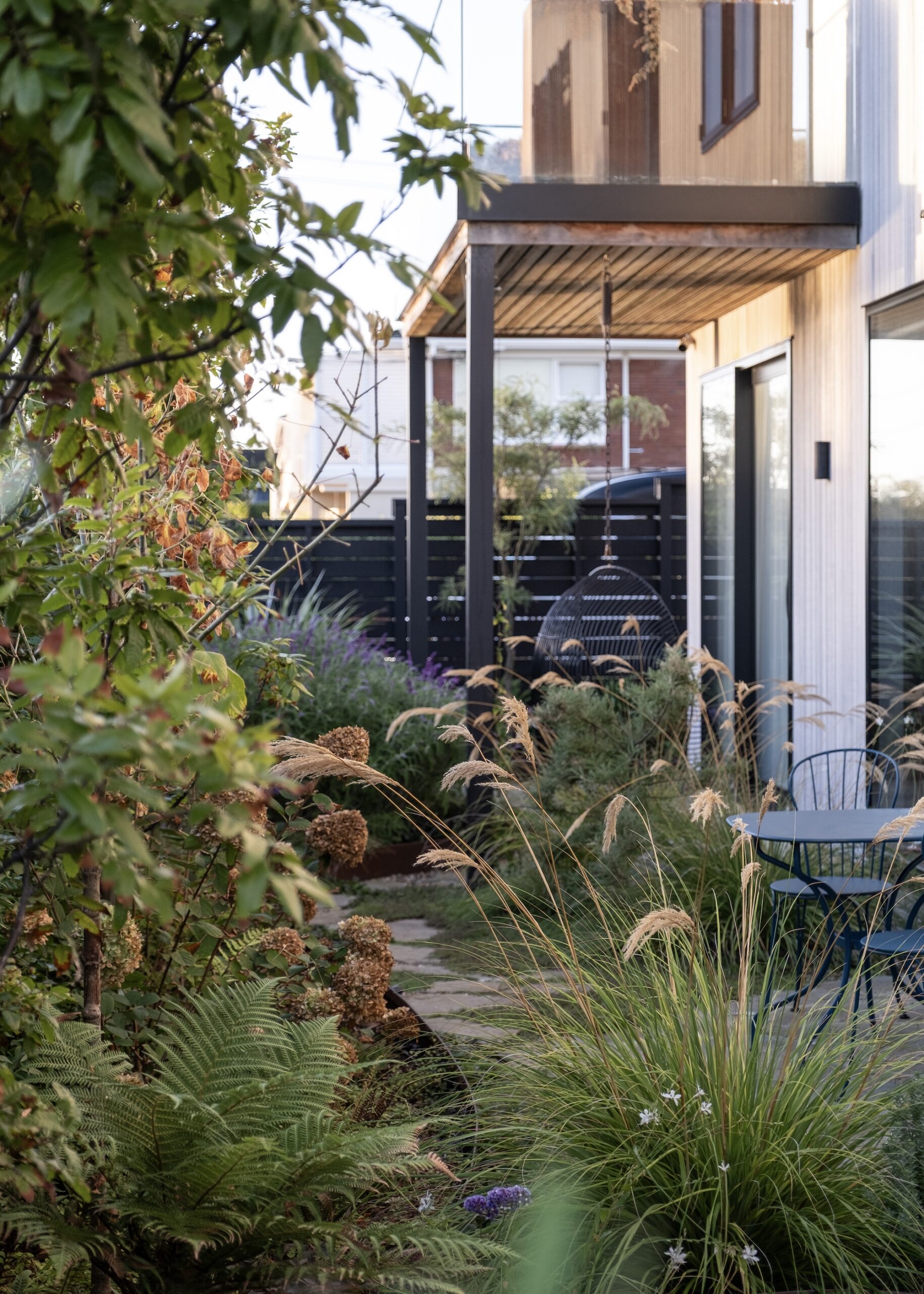 Rich garden with a mix of shrubs, grasses, and a visible house façade