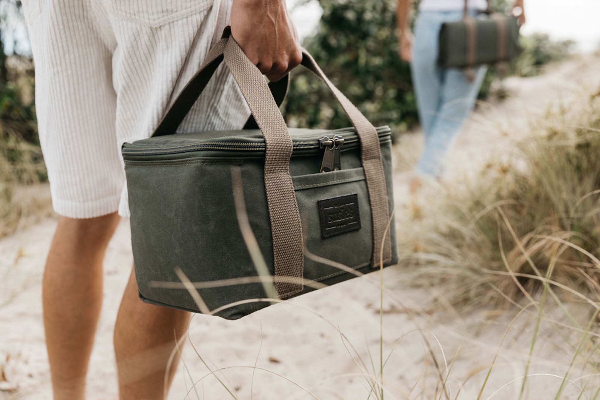 Susie’s Bags olive green cooler bag carried along a sandy path