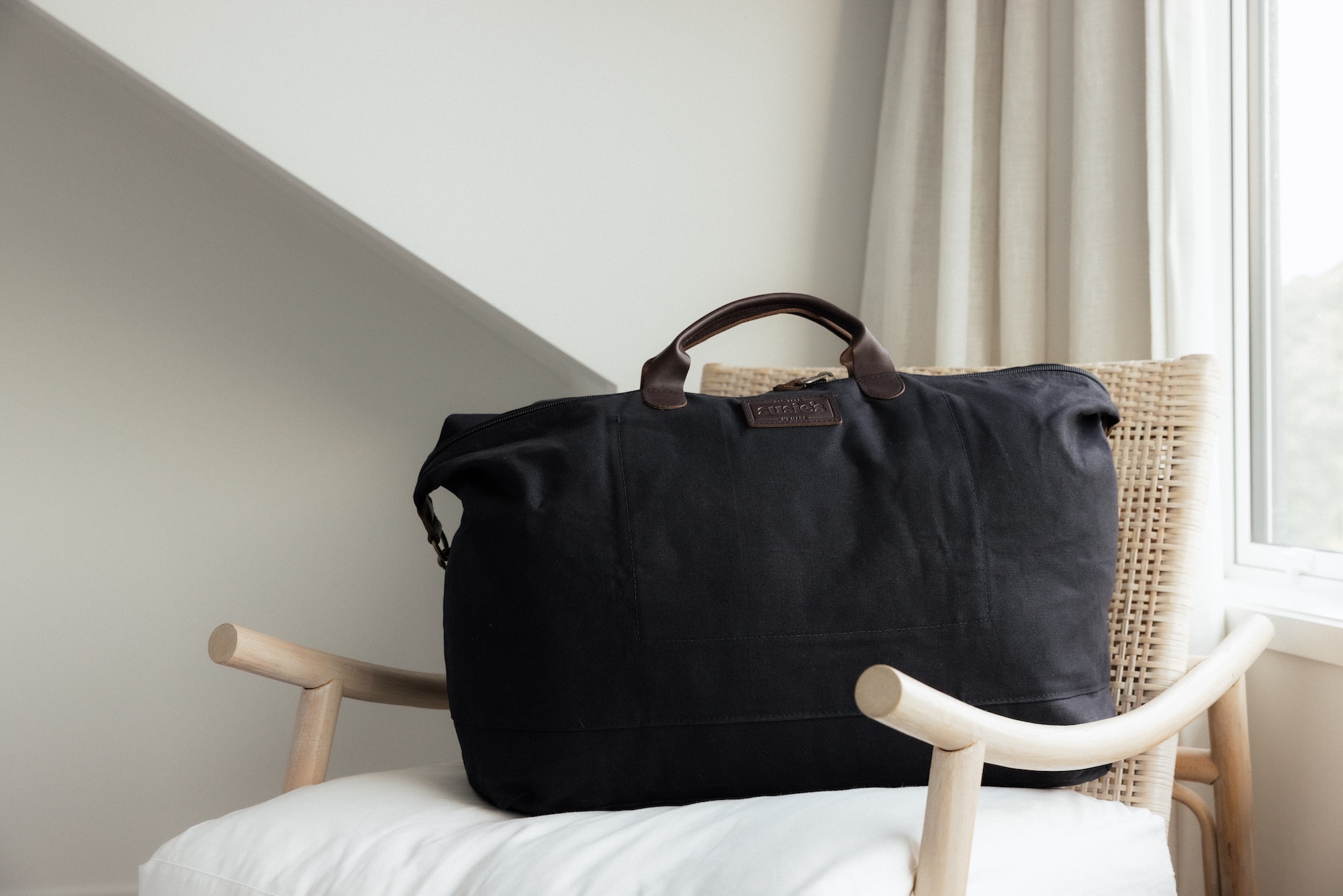 Susie’s Bags black weekender bag on a white armchair