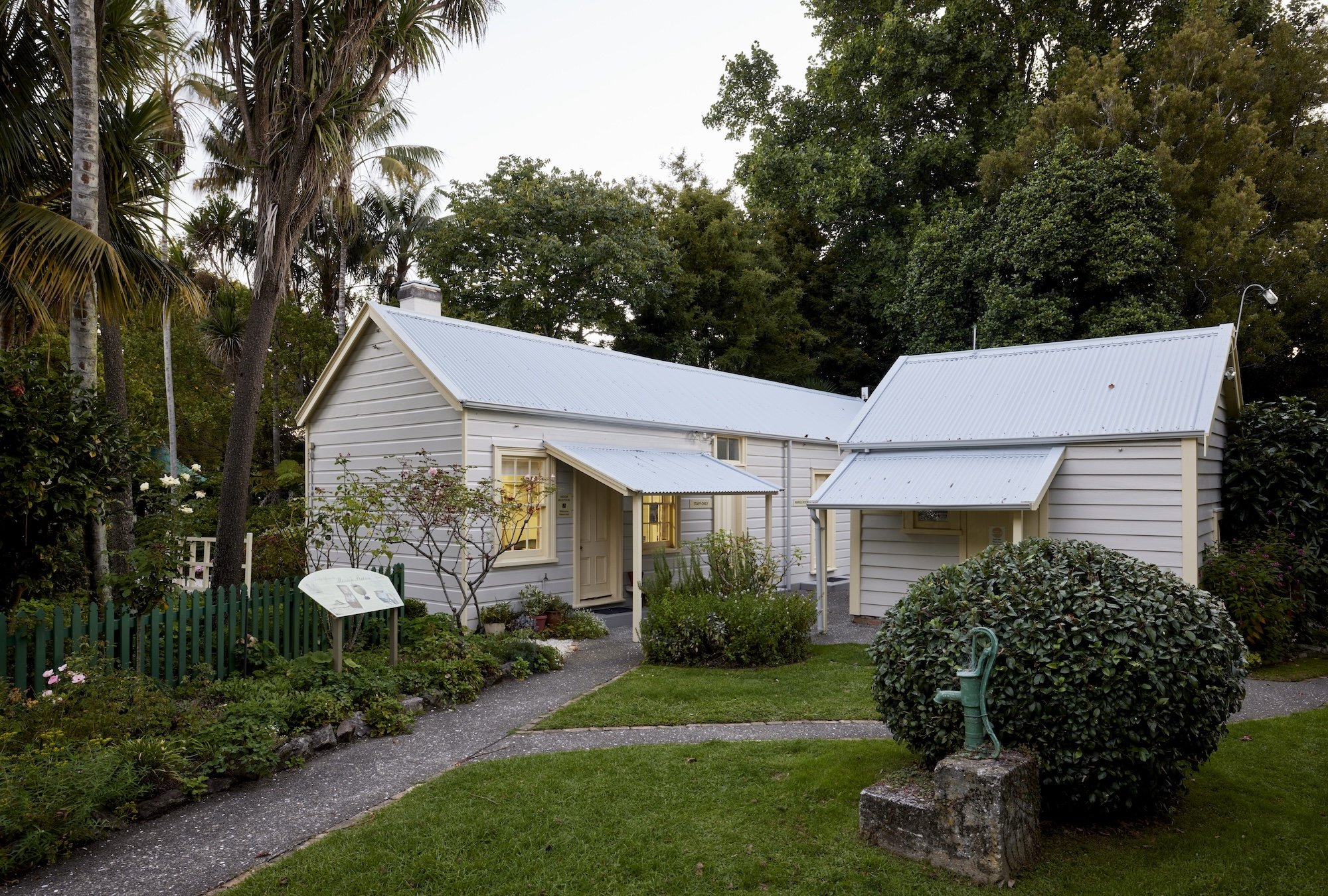 Classic colonial-style house with pitched roof, white siding, and manicured garden.