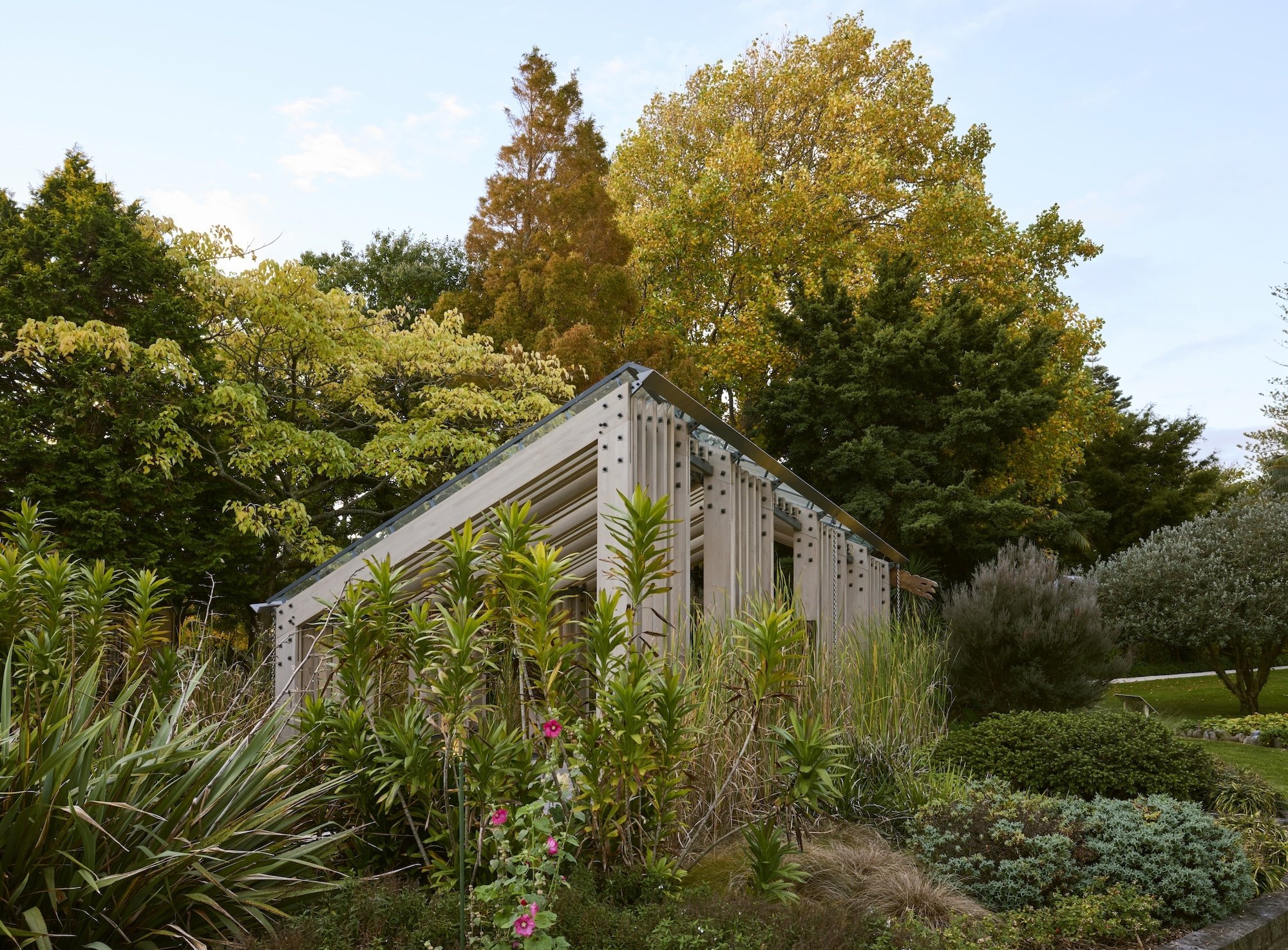 A structure surrounded by autumn trees and lush plantings.