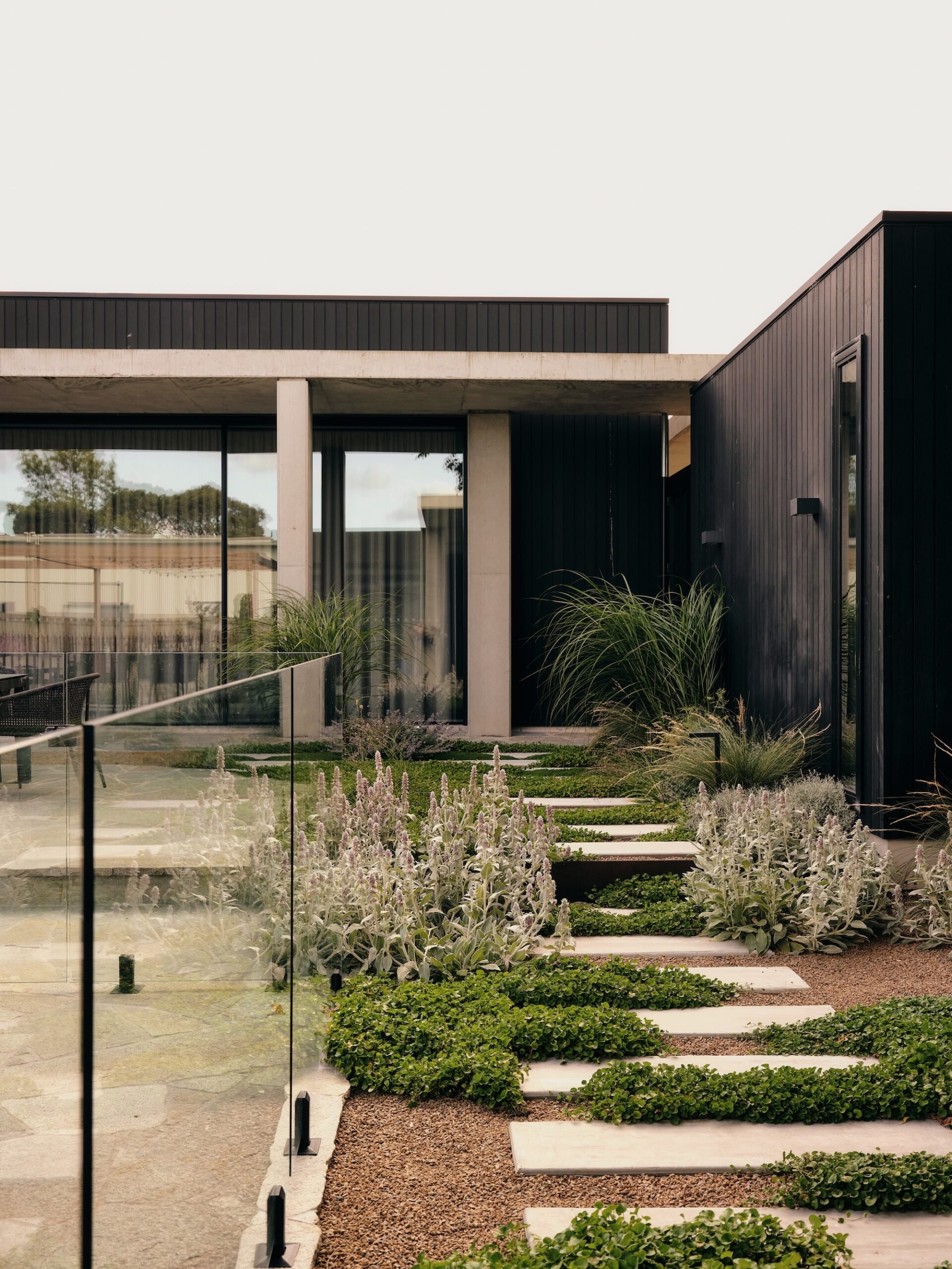 Stepping Stone Garden Entrance – Phillip Withers Contemporary front garden with stepping stone path leading to a modern black-clad home