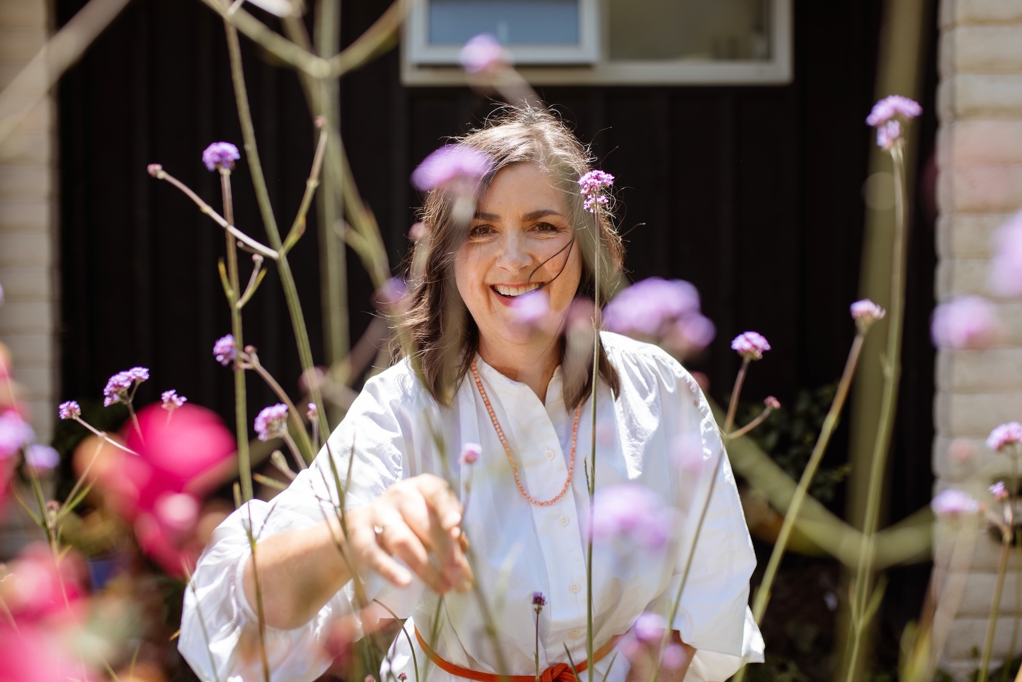 Katherine English in her garden with spears of Verbena bonariensis in the foreground