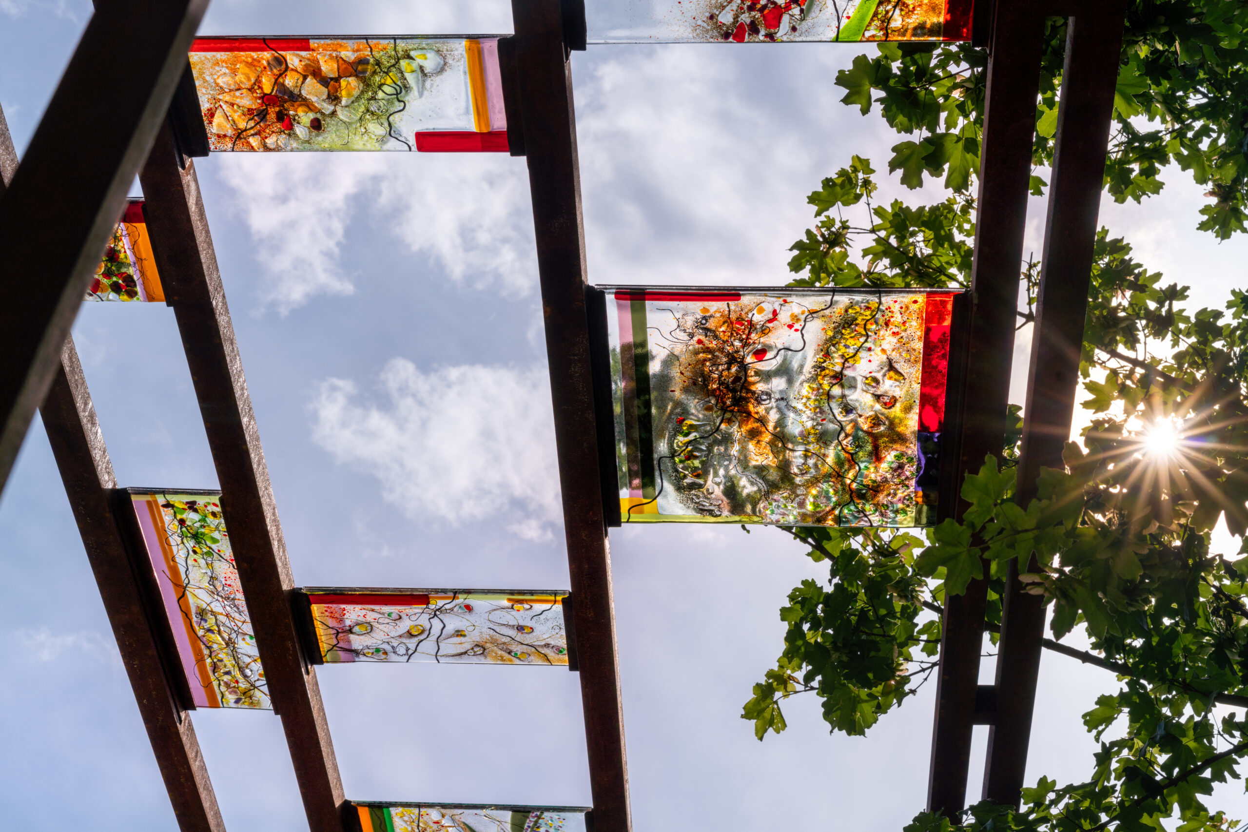 Looking up through vibrant glass panels in RHS CFS The Children's Society Garden.