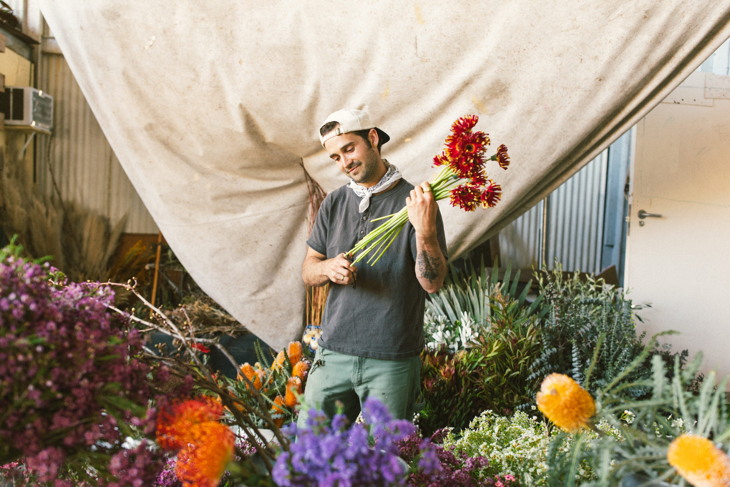 Spencer Falls of The Unlikely Florist in his flower studio surrounded by colourful cut flowers