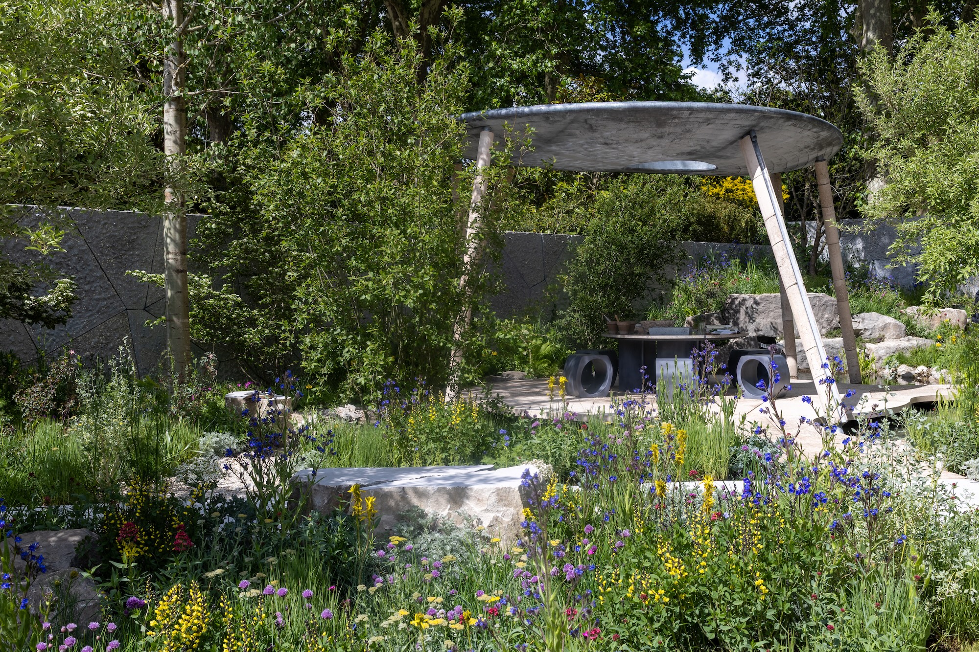 Landscape shot of RHS show garden featuring contemporary solar pavillion structure surrounded by colourful planting and stone details