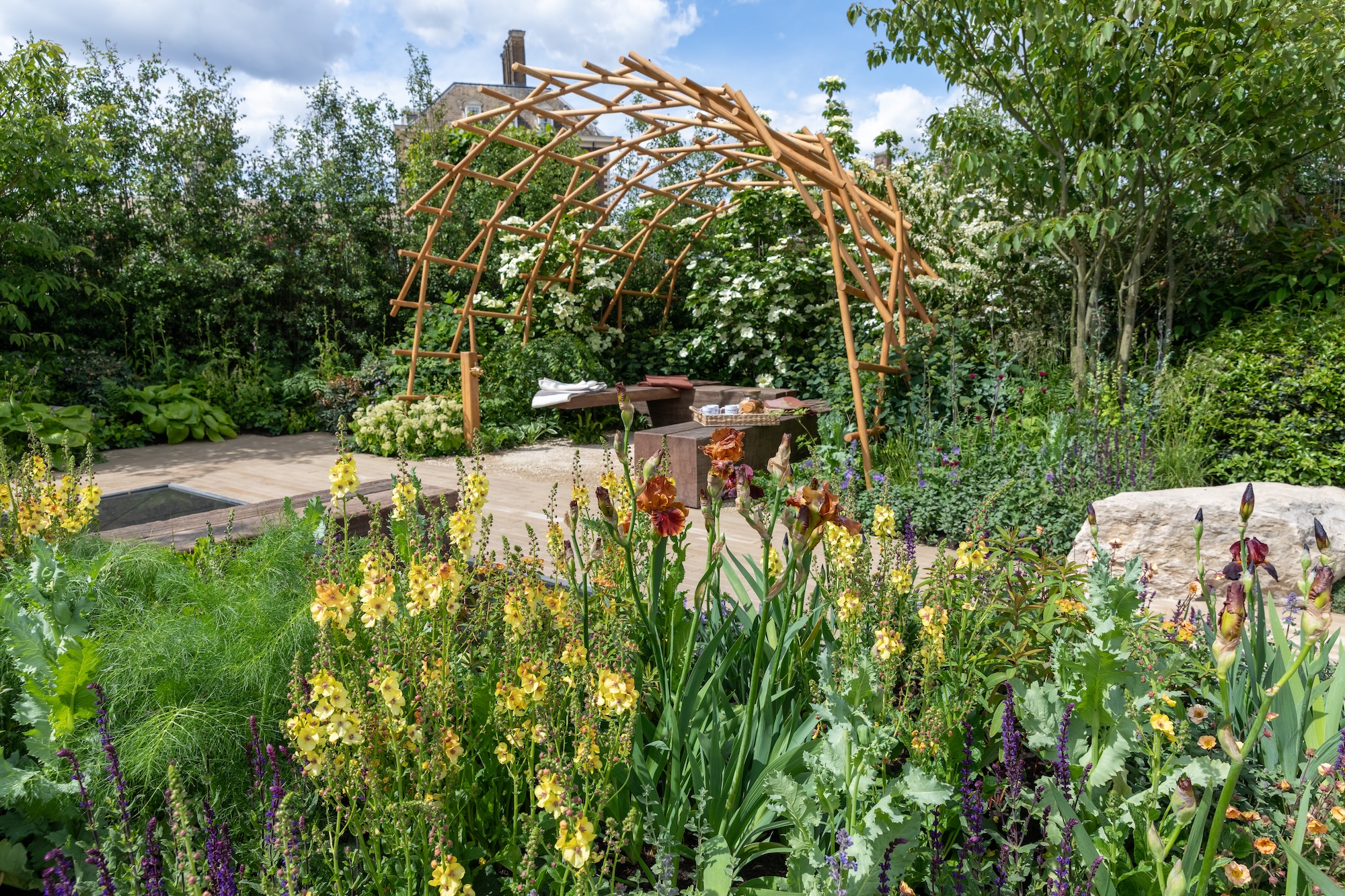 Yellow flowering perennials and a timber garden structure among layered planting for Trussell’s Together Garden